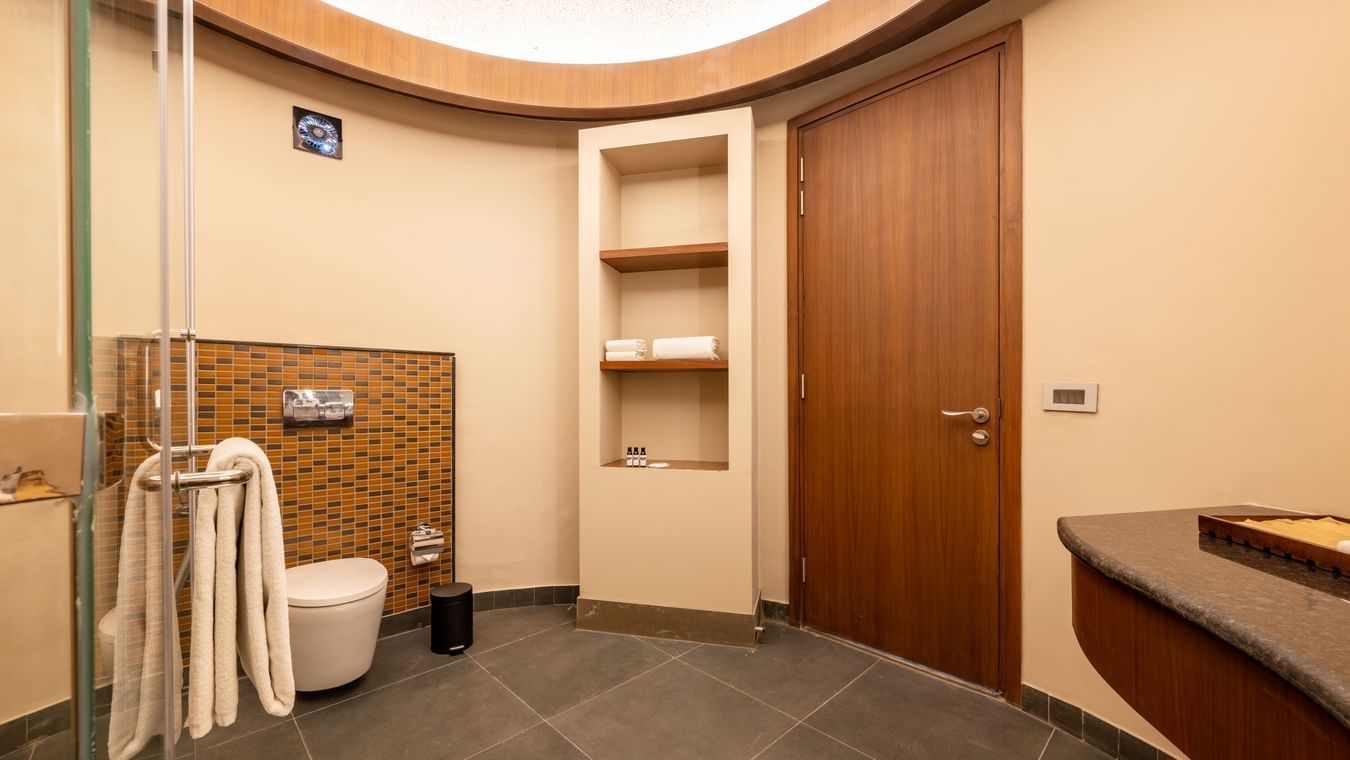 Bathroom of Earth Villa at Ananta Spa & Resort, Ajabgarh featuring a spacious shower area with a shelf, shower fittings, and a glass partition.