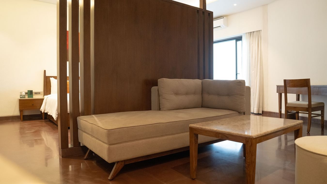 Modern living area with a sofa, coffee table, and wooden partition at Ananta Spa and Resort, Ajabgarh.