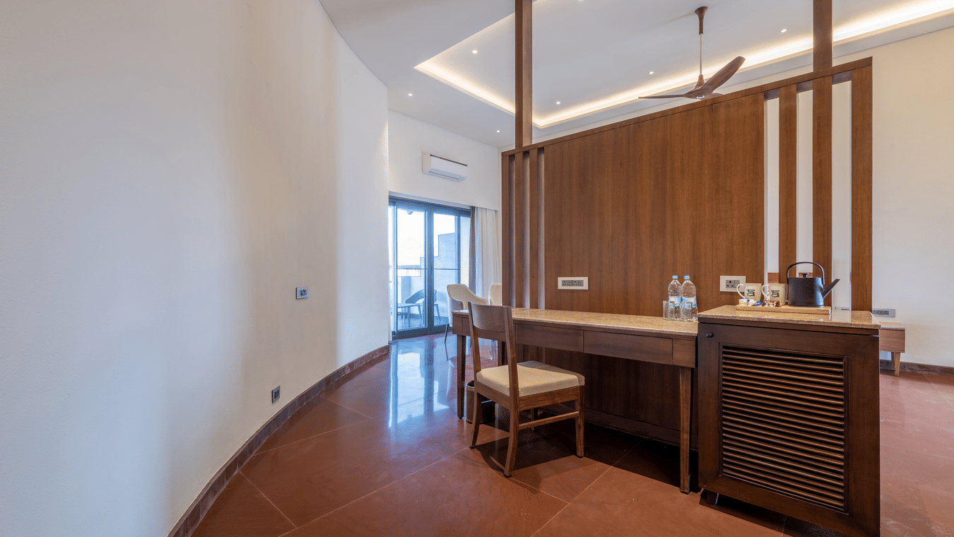 The Fire Villa with Balcony at Ananta Spa & Resort, Ajabgarh featuring rich wooden interiors, a stylish vanity and minibar area, high ceilings with ambient lighting, and a private balcony overlooking the serene surroundings.