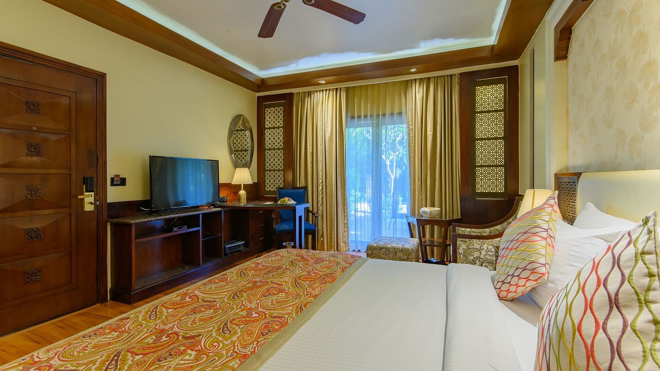 The interiors of our Premium Cottages in Pushkar featuring a balcony, a comfotable bed, sofa chairs 162