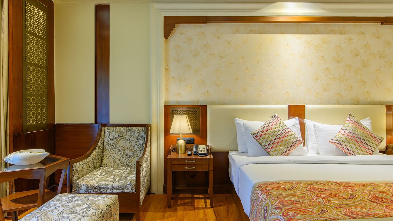 The interiors of our Premium Cottages in Pushkar featuring a balcony, a comfotable bed, sofa chairs 166