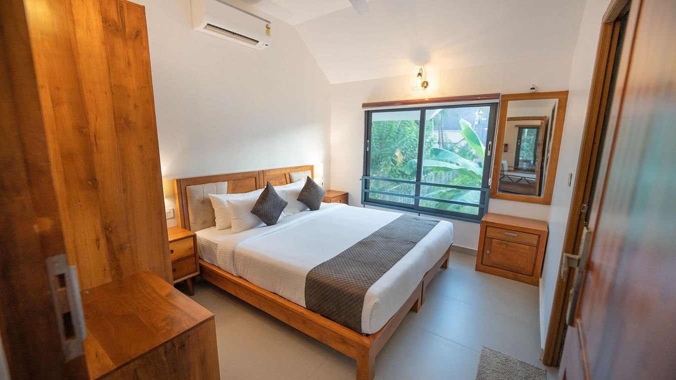  Side view of room with window overlooking the lush greenery and a bed with wooden wardrobe at Feel Free Retreat, Wayanad