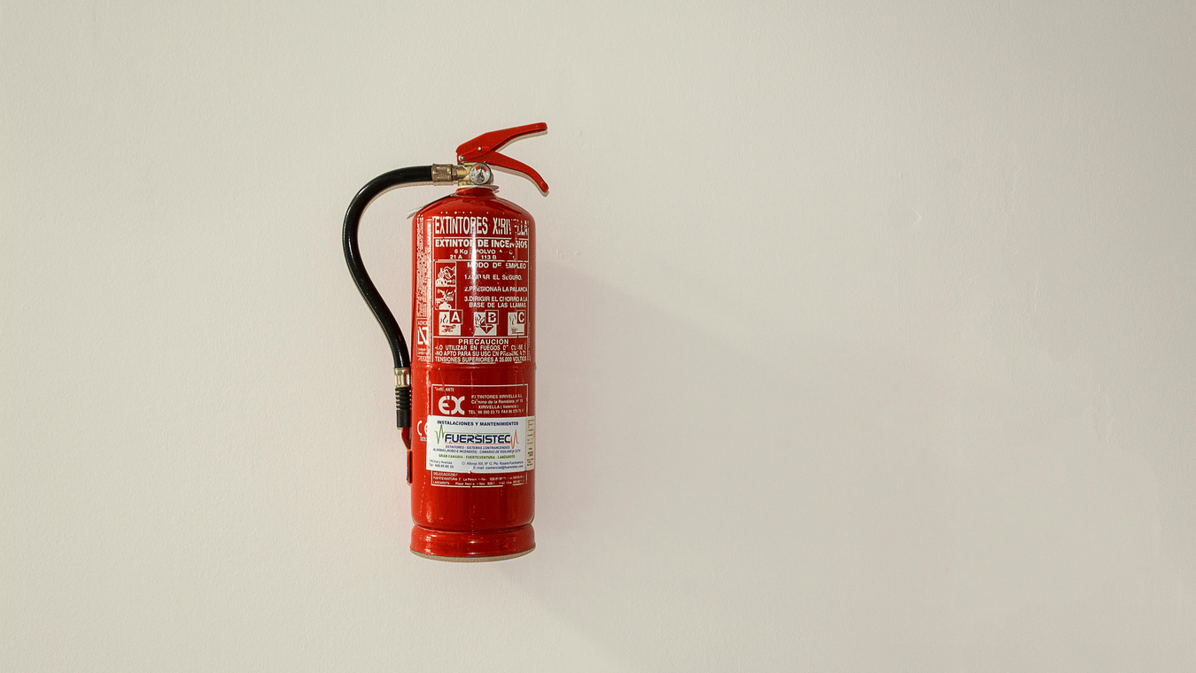 Red fire extinguisher mounted on a clean, light-coloured wall.