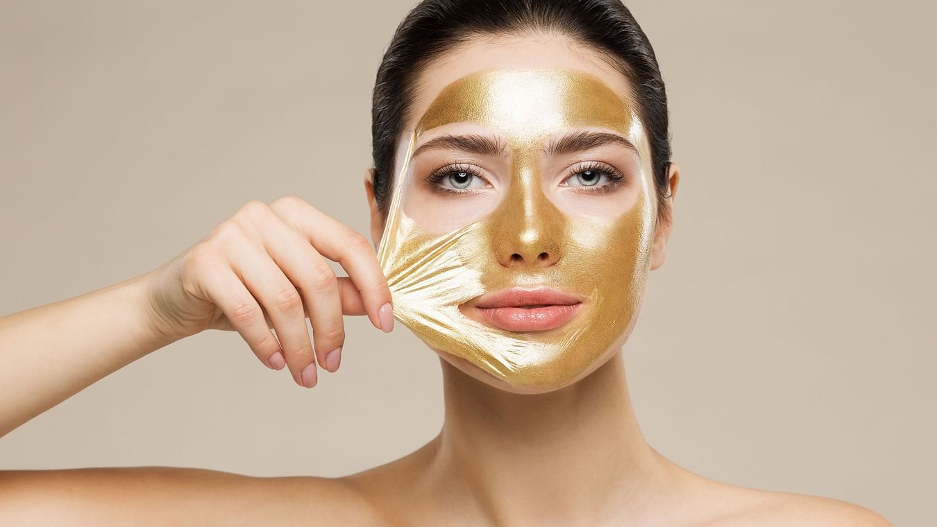 A model peeling off a gold face mask - Best Facial in Raipur