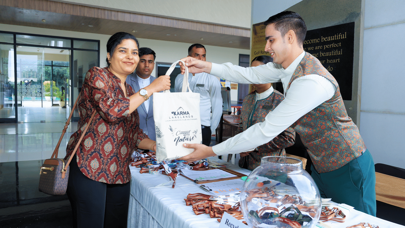 Attendee receiving a gift bag at a registration counter - Karma Lakelands.