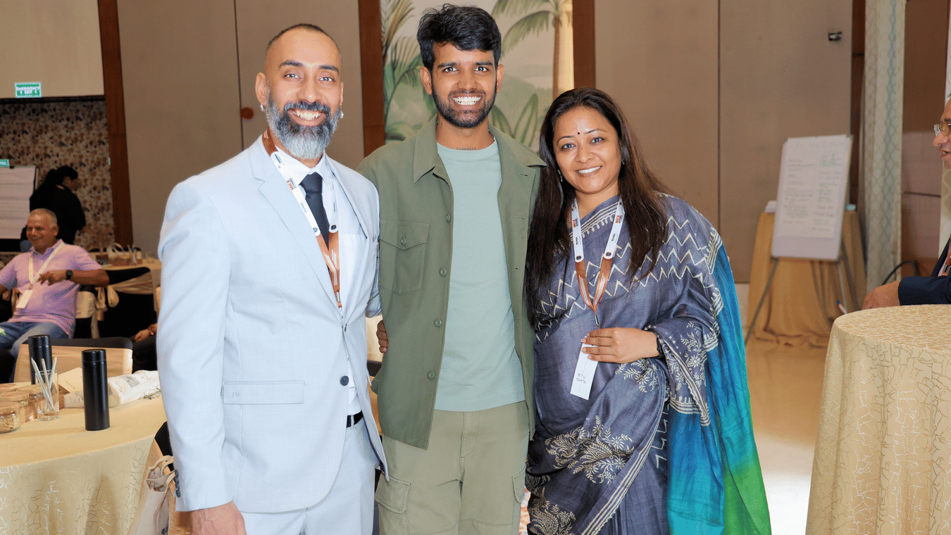Three individuals smiling at an indoor gathering - Karma Lakelands.
