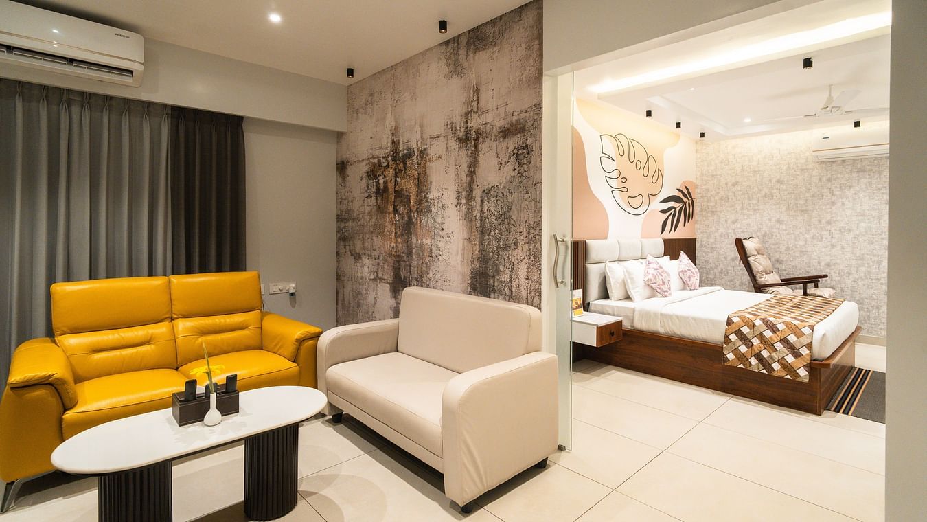 An image of a room with a plush bed in the bedroom and sofas placed around a coffee table in the living room - MGM Whispering Meadows