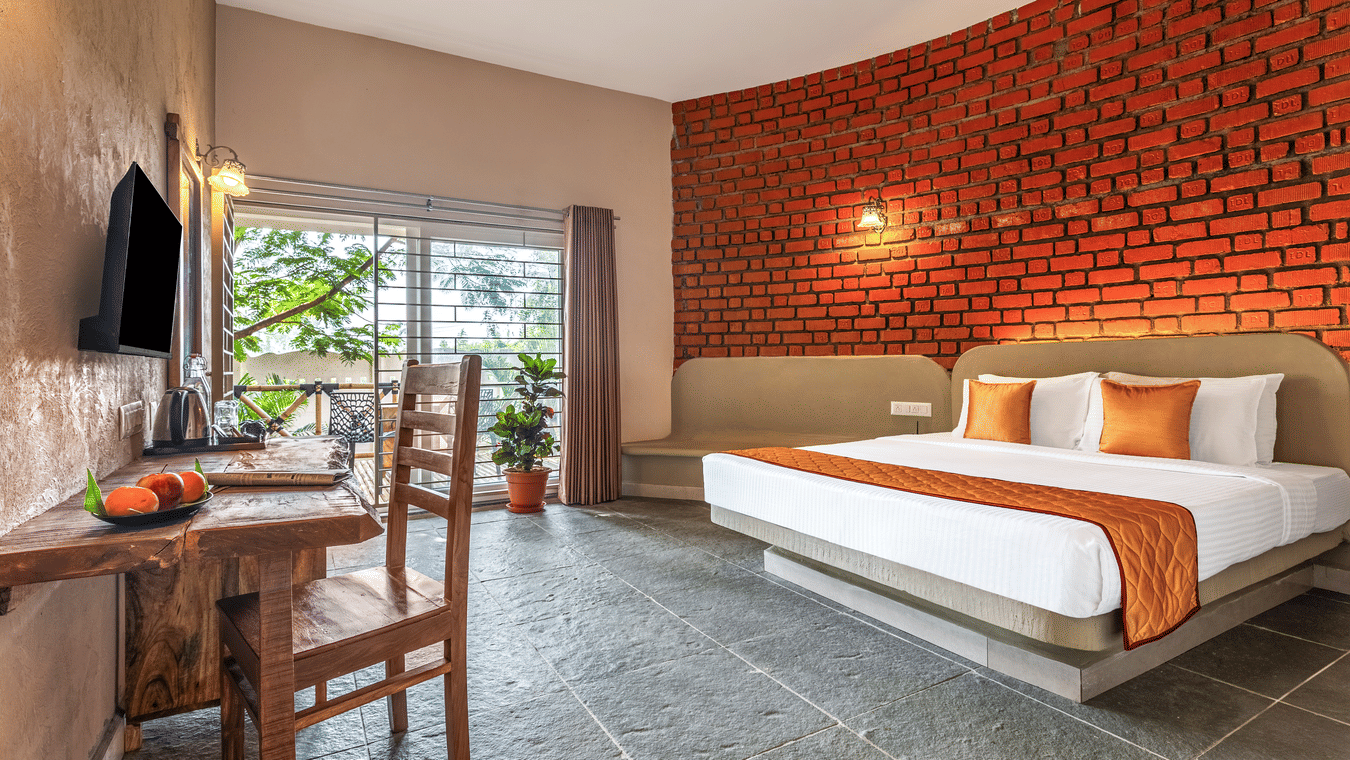 View of a suite interior showing the seating area and sliding doors to the balcony - Nature Trails Ashoka Resort Hampi
