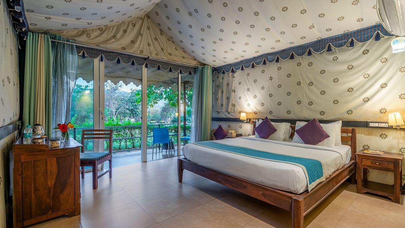 A luxurious bedroom with a canopy ceiling, patterned walls, and a scenic view through large windows.