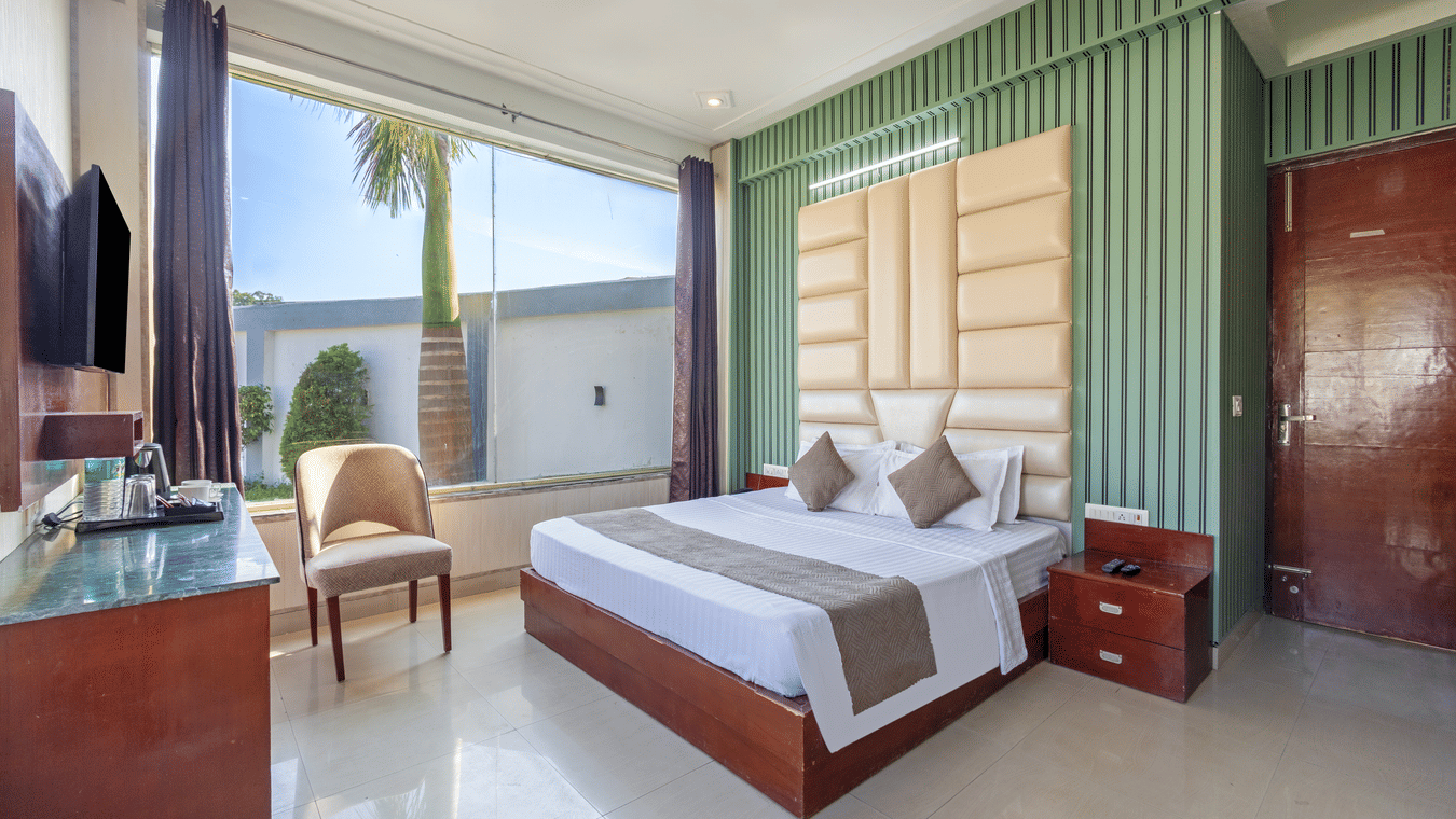 A contemporary hotel bedroom with teal green accent walls and a comfortable king-size bed - Nature Trails Rishikesh
