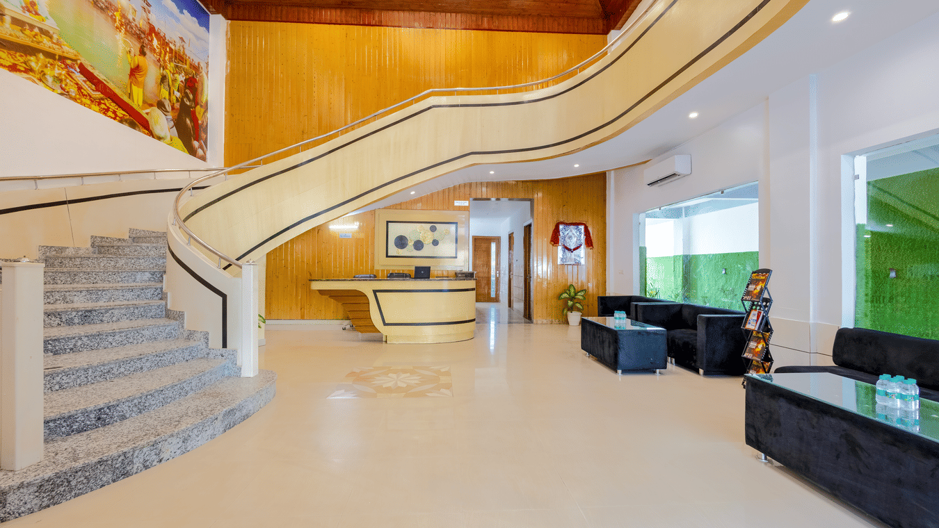An expansive hotel reception area with a curved staircase, marble flooring, and wood-panelled accents - Nature Trails Rishikesh