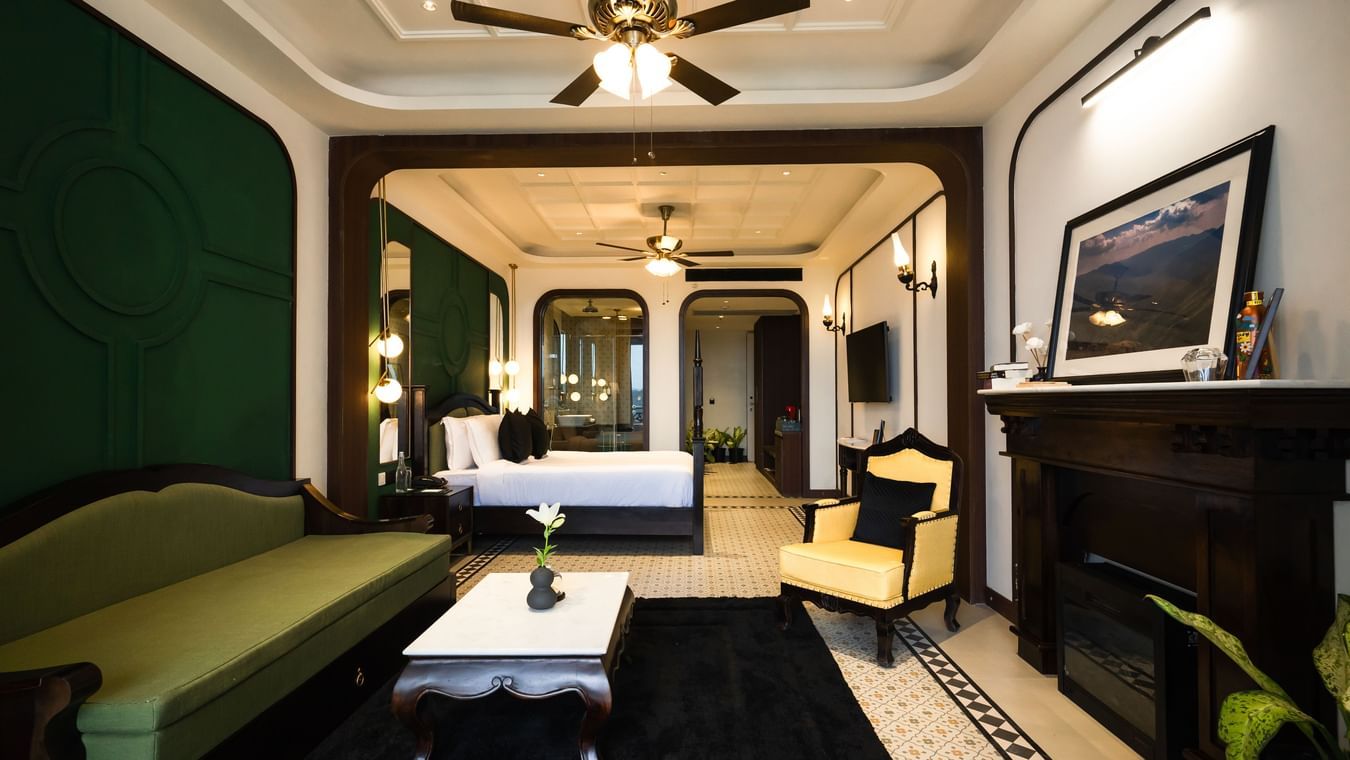 Bedroom with king size bed, flat TV screen, chair, and sofa - Polo Cherrapunjee Resort