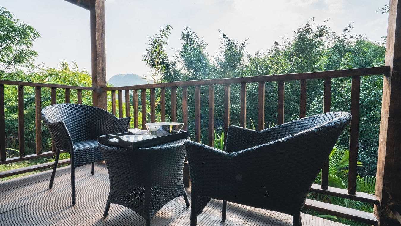 2 chairs and a small table on the balcony at jungle wooden cottage - The Ananta Udaipur