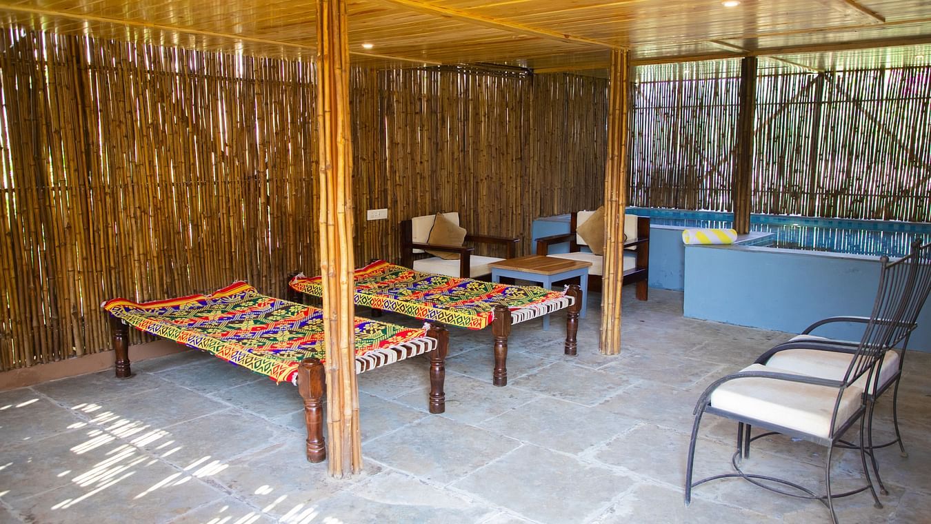 Charpoys and chairs under a thatched roof