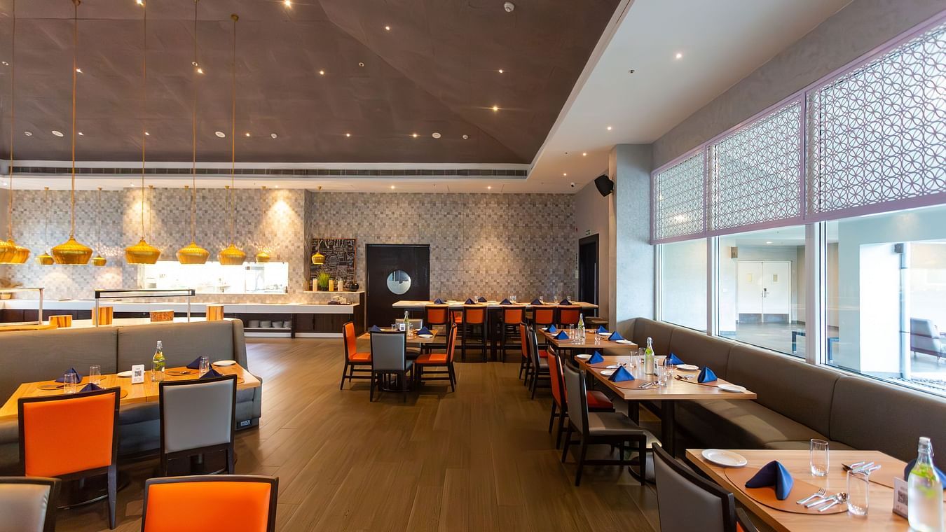 A modern, well decorated restaurant interior with tables and chairs arranged in a spacious layout at THE RESIDENCY TOWERS RAMESWARAM.