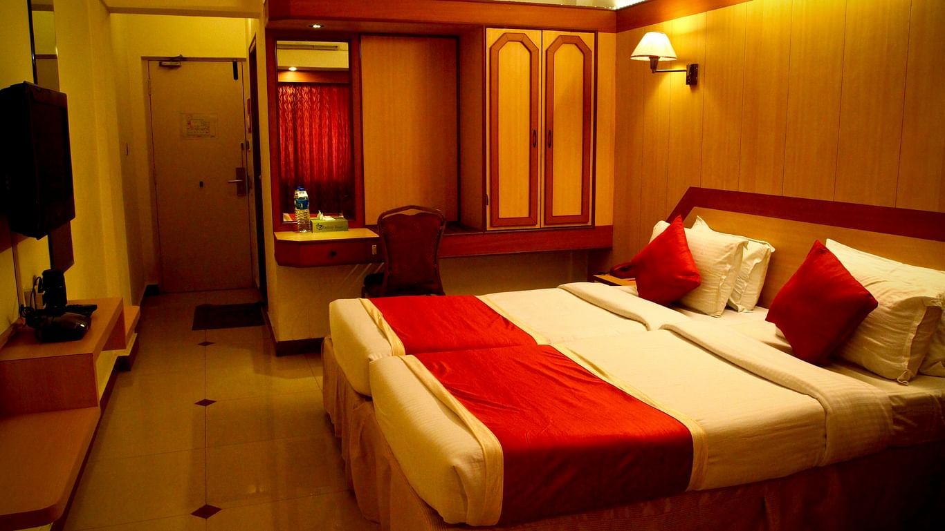 A room decked with comfy double bed with a maroon duvet - Hotel Swagath, Bangalore