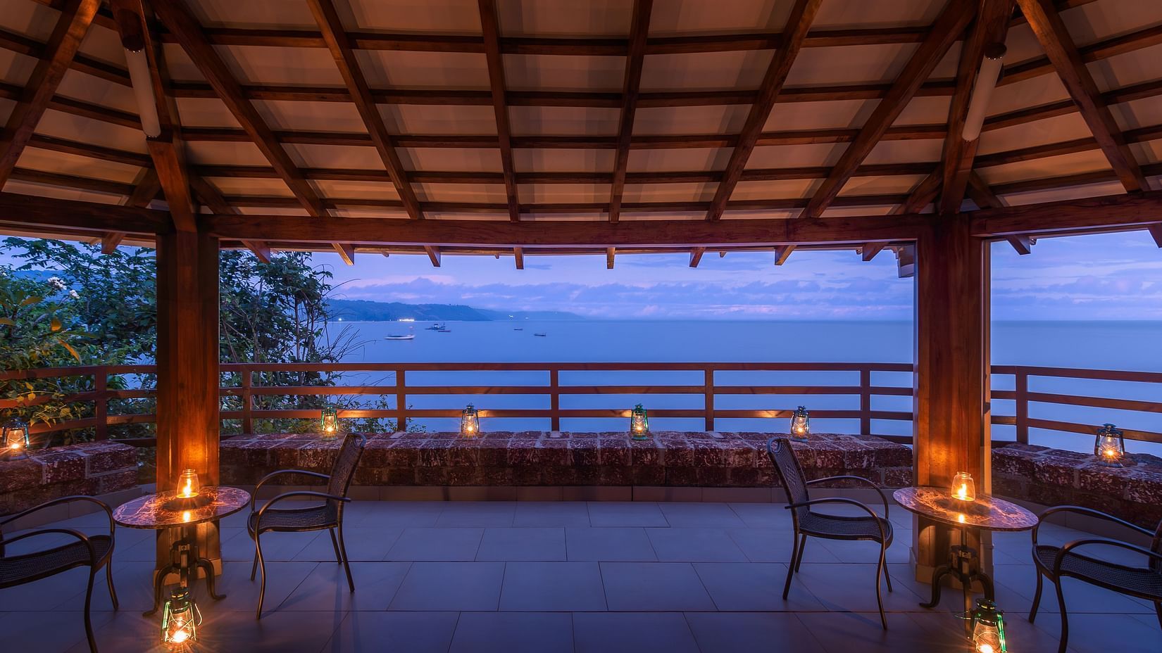 A wide-angle shot of of a gazebo overlooking the ocean seen featuring a candle light seating arrangement - Highland Sarovar Portico, Sindhudurg