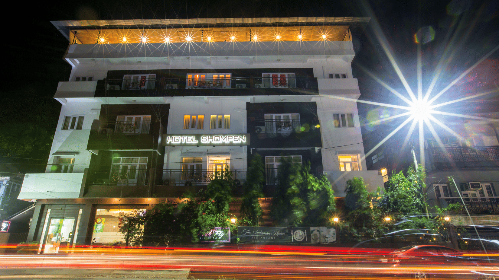 The facade of Hotel Shompen, a 5-star hotel in Port Blair, Andaman, with lights on during the night.