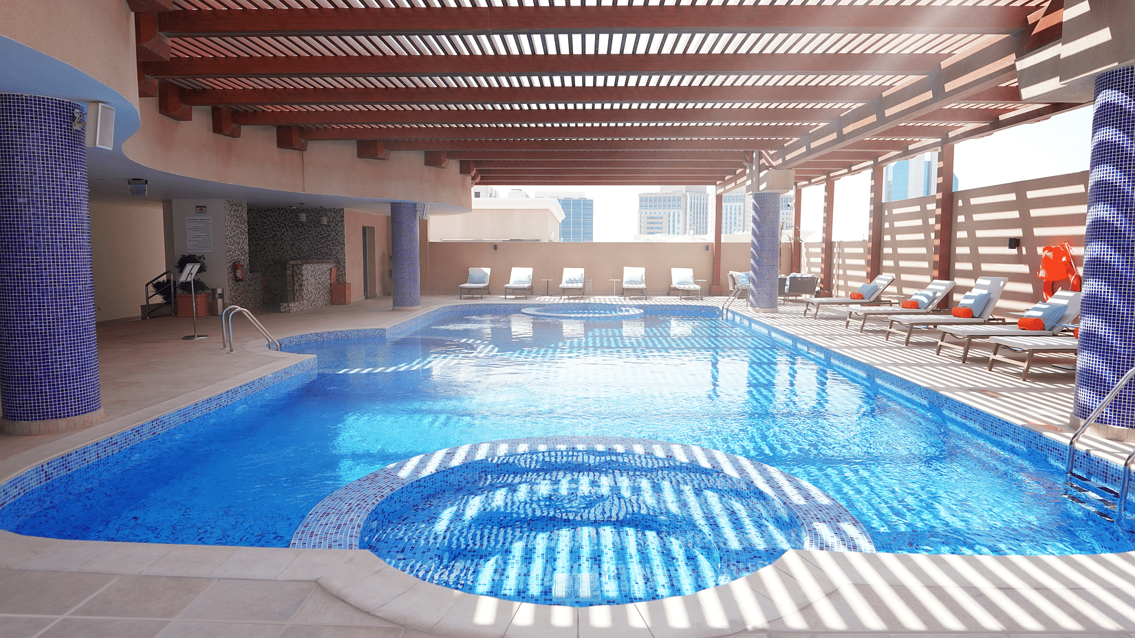 an overview of the swimming pool with sun's rays hitting the swimming pool - La Maison Hotel, Doha.