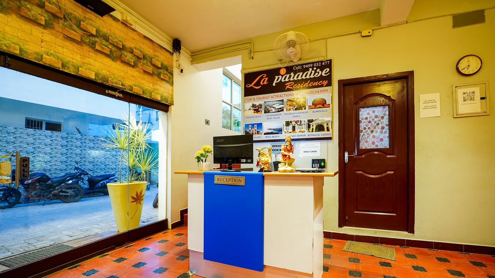 A front view of desk in the reception area with a glass door | La Paradise Residency, Pondicherry