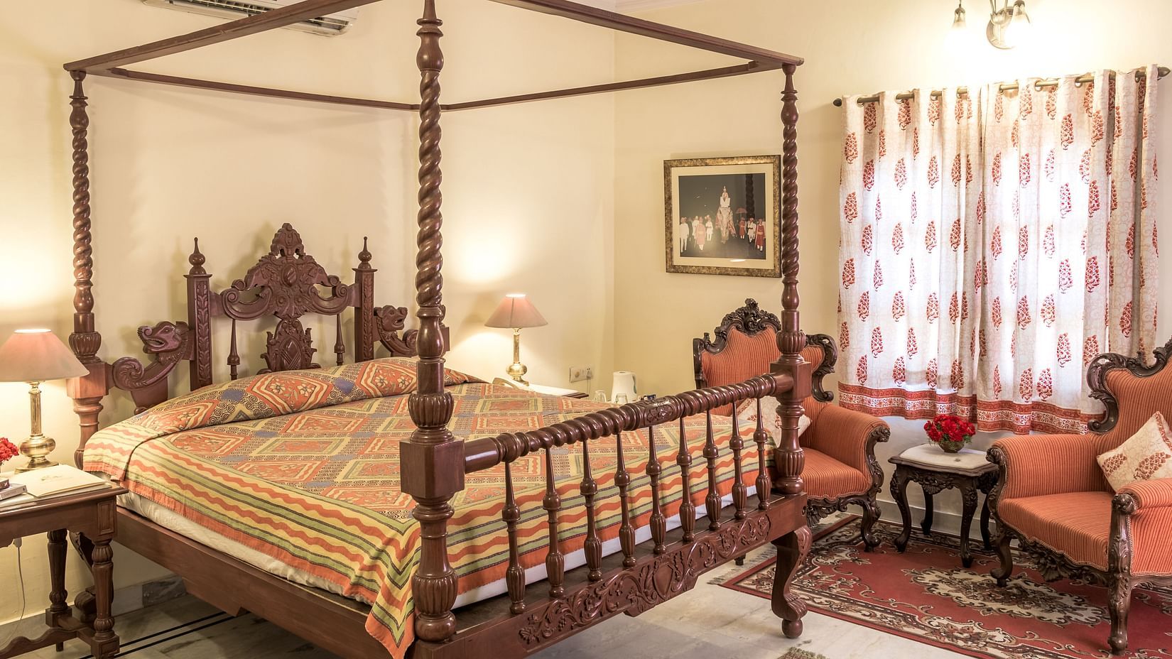 A king bed with side tables, lamps and single seater sofas next to it inside Standard rooms - Mandawa Haveli, Jaipur