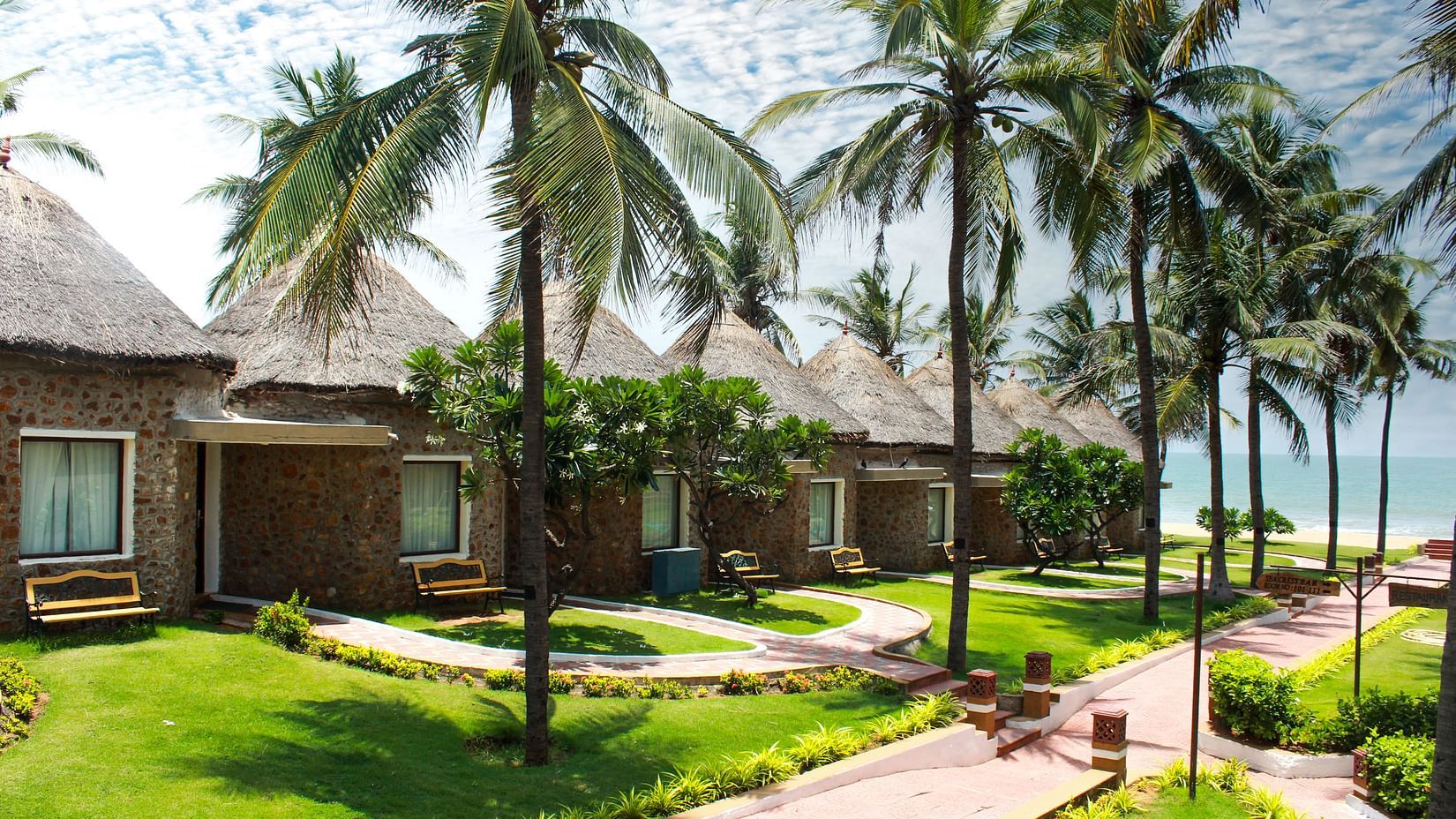 Cottages with the sea in the background and coconut trees stretching out to the pavements