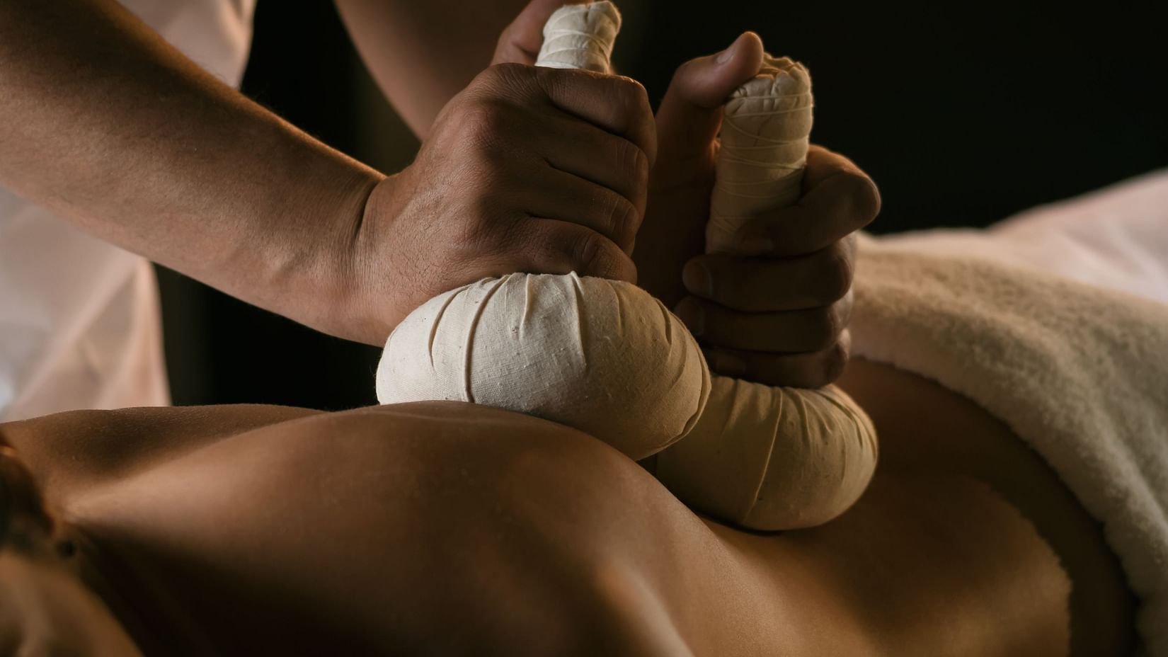 A massage therapist uses two hands to treat a person’s back