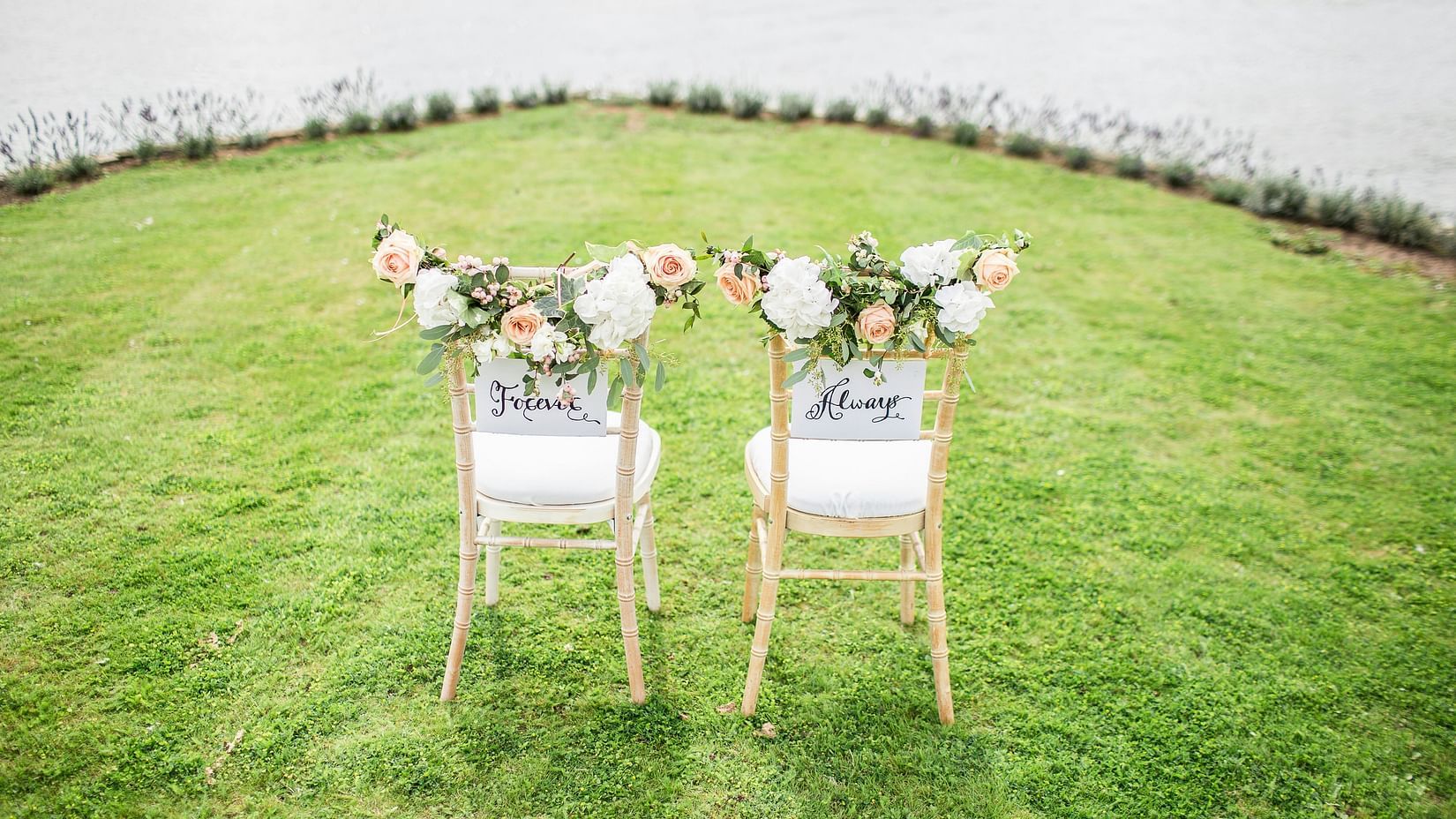 a manicured garden with two chairs having bouquets on it