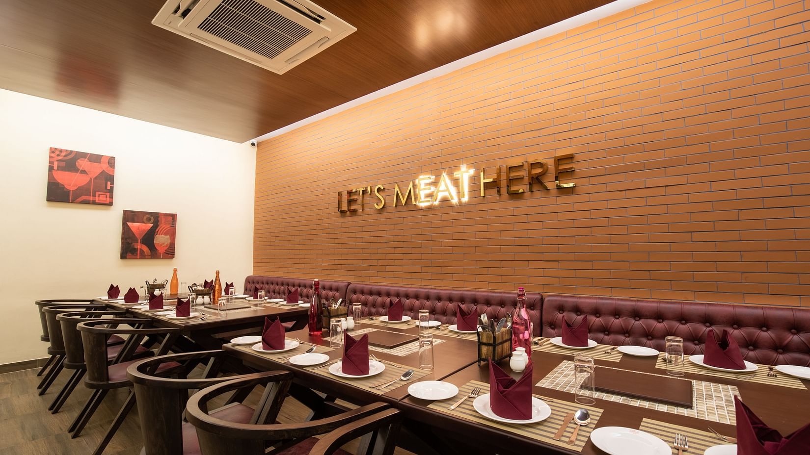 A well-lit restaurant with set tables, wooden chairs, and a wall with LET'S EAT HERE lettering - Jenneys Residency, Coimbatore