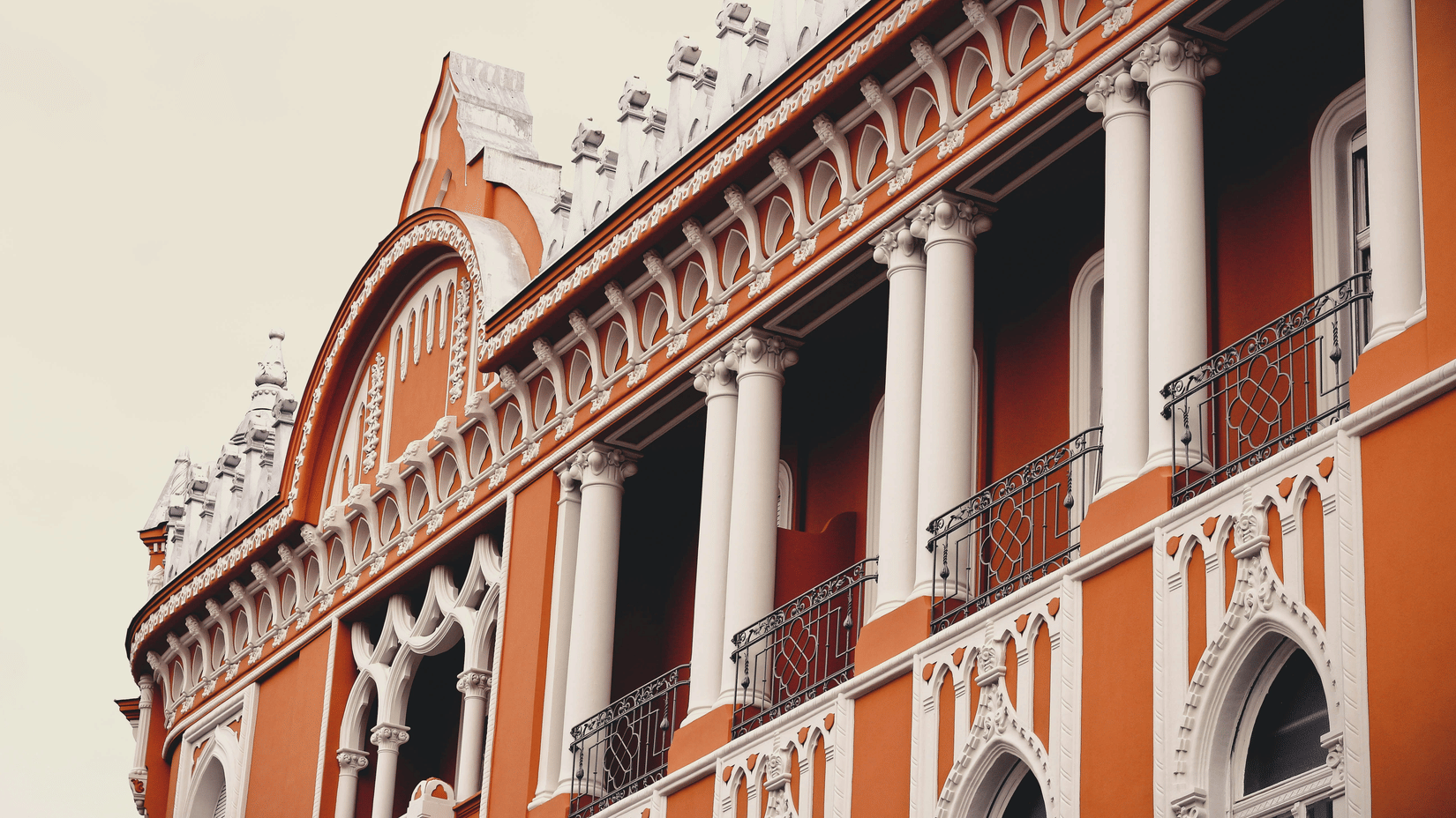 Detailed architectural perspective of a colonial facade adorned with tall white pillars, delicate arches, and decorative railings