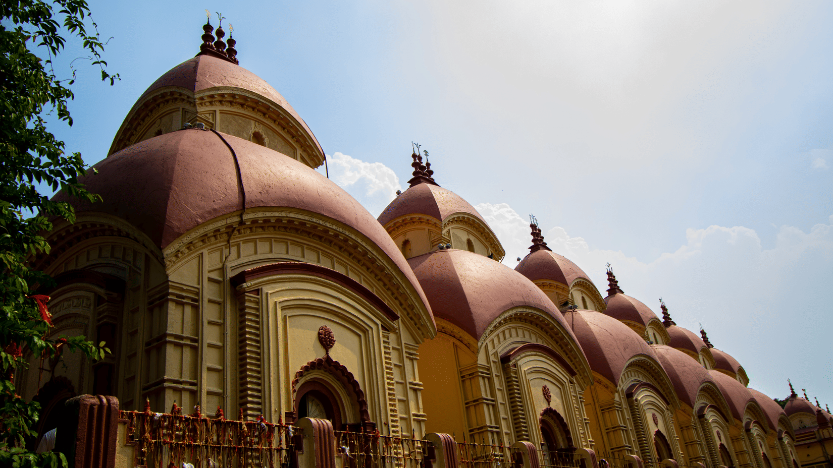 a facade view of the famous Dakshineswar Kali Temple with pagoda shaped roofs captured during the day.