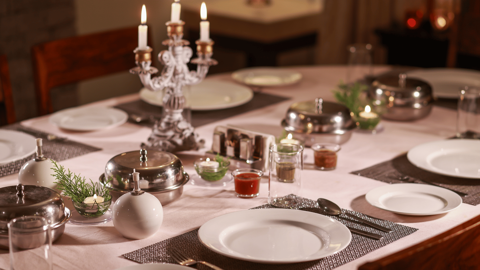  Elegantly set dinner table with candlelight, fine china, and silverware, ready for a formal meal.