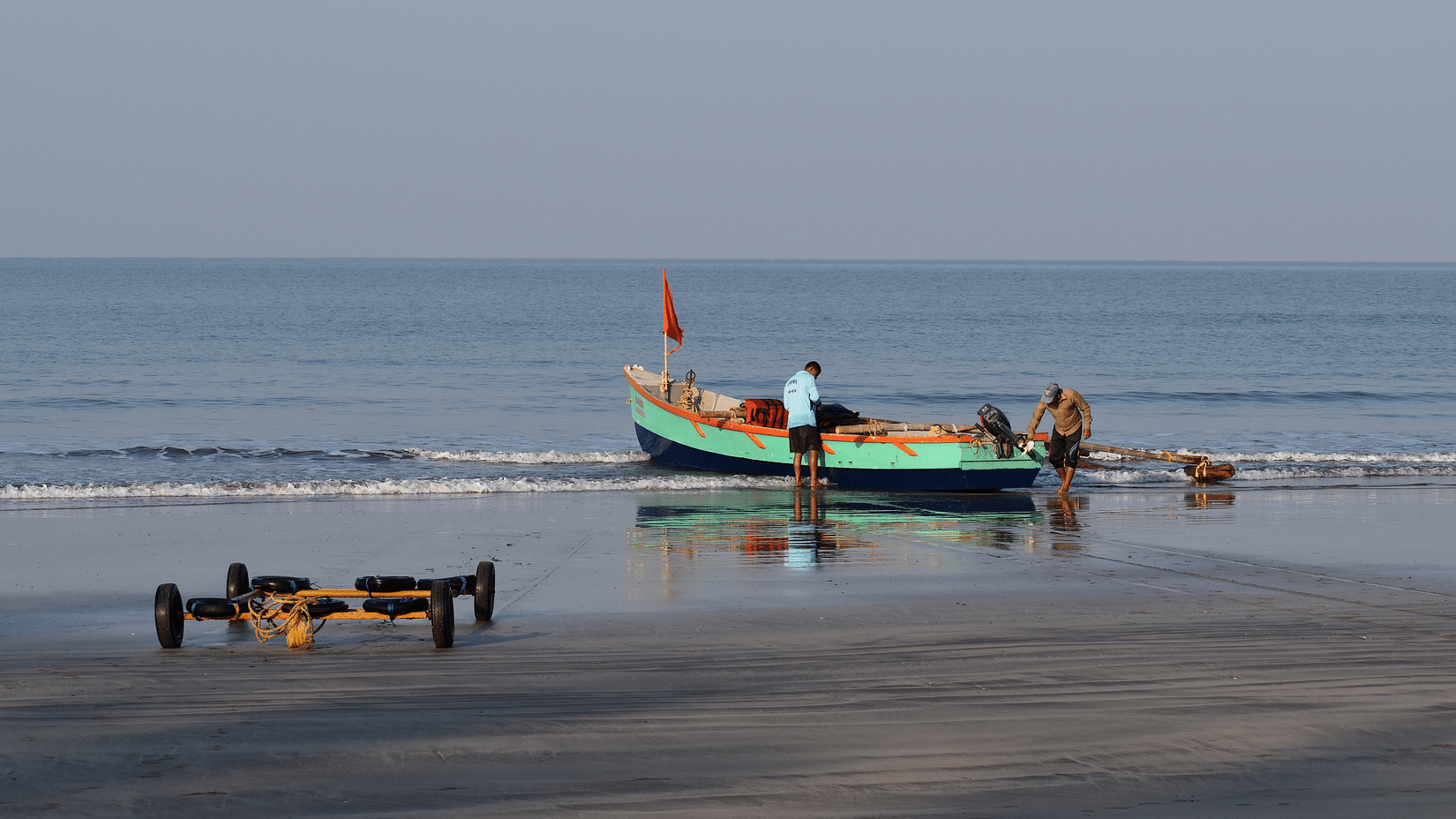 a man taking care of his boat on the beach in Dapoli