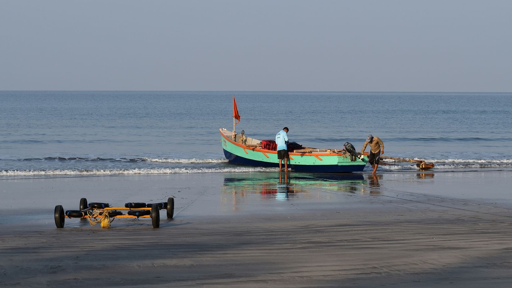 a solitary boat parked on the shoes of Dapoli beach with people on it
