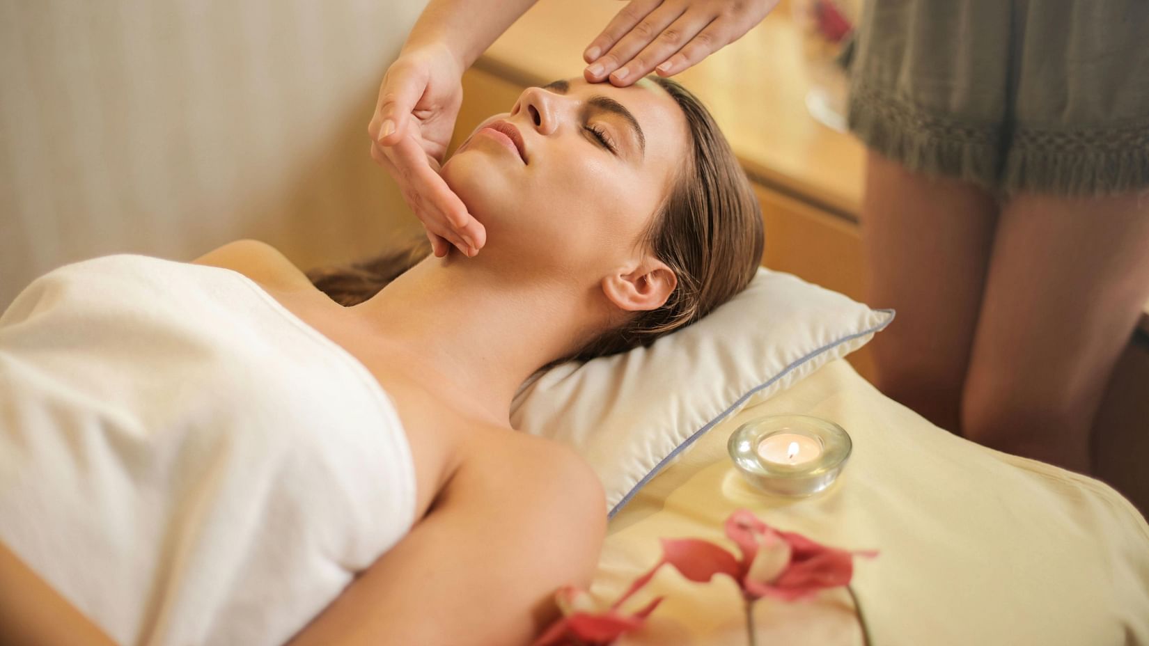 An image showcasing the spa experience, featuring a person lying on a treatment bed receiving a relaxing therapy.
