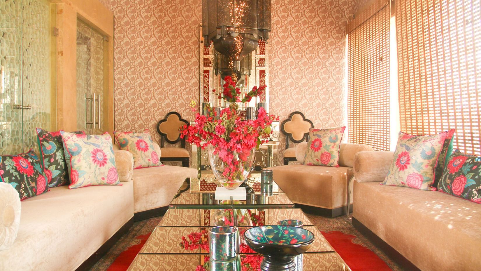 A luxurious seating area featuring sofa set in a U shaped setting, elegantly designed cushions, and table at the centre where flower vase and decorative bowls ae placed - Sonaar Haveli, Jaisalmer