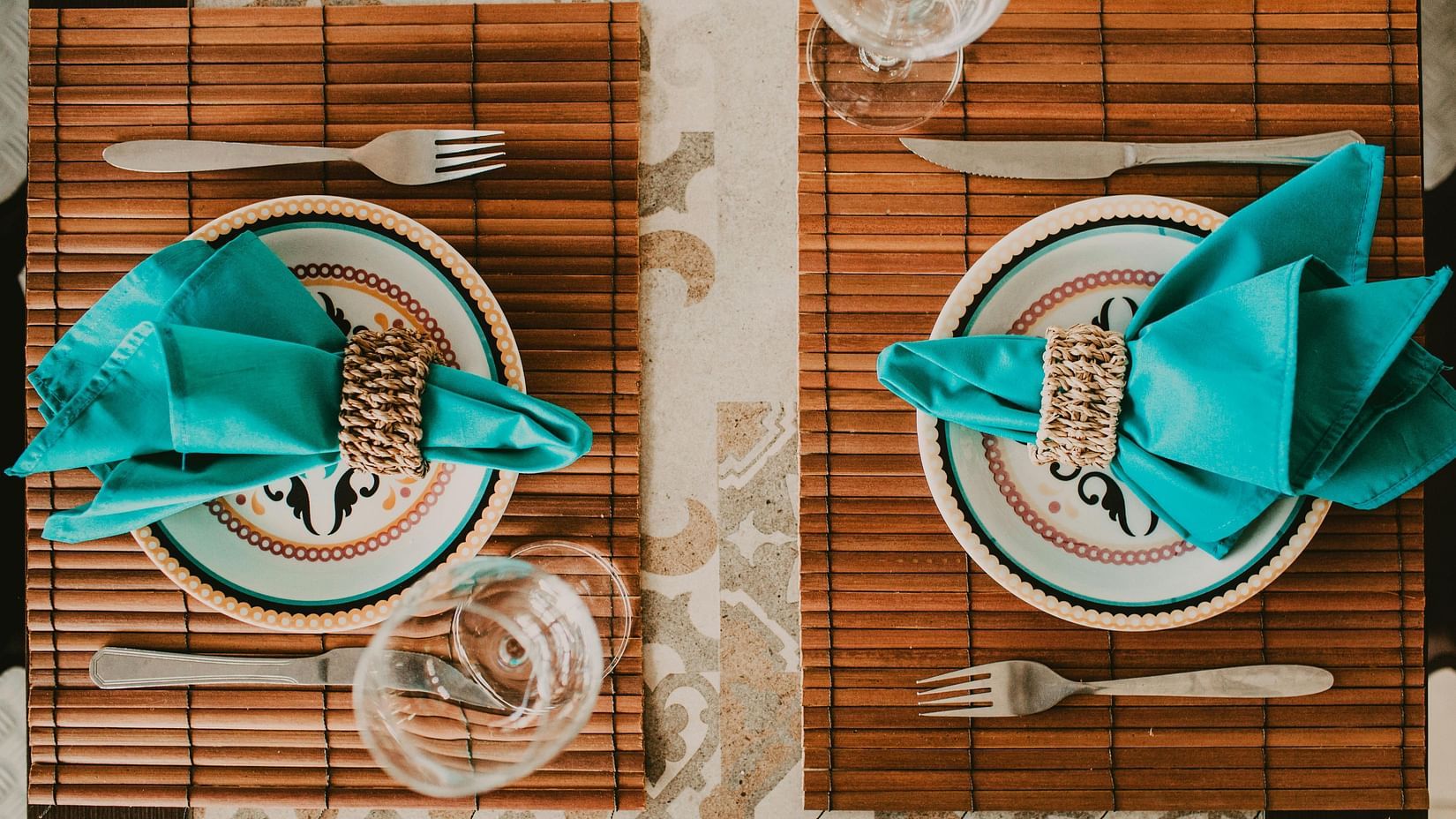 An image of a table laid out with two plates, two glasses, napkins, and cutlery