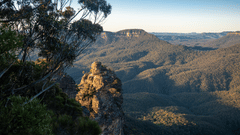 A scenic overlook with a rocky outcropping in the foreground and a vast valley of rolling hills in the distance.