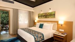 view of a double bed and night stand in the Cottage at ABN Sarovar Portico, Jim Corbett
