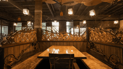 A side view of table with multi-seating chair and wooden ceiling with overhead lamps at Adamo The Village.