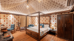 Elegant bedroom with four-poster bed, patterned wallpaper, wooden flooring, wardrobe, blue chairs, and telescope by window.