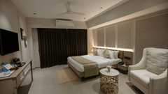 A comfortable hotel room with a neatly made bed, seating area, and curtains - Biznotel By Pride Surat