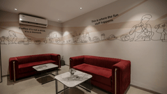 A modern lounge with red sofas, a coffee table, and wall art - Biznotel By Pride Surat