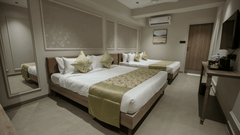 Modern twin bedroom at Biznotel by Pride Surat featuring two double beds, wall molding, and air-conditioning.