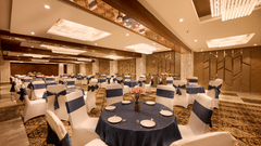 A banquet hall with round tables covered in blue cloth and chairs around it