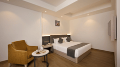 A hotel room with a bed, a chair, a coffee table and ambient lighting