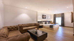 A hotel suite with a sofa beside a bed and a window providing light