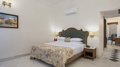 Fateh Vilas Udaipur - Interior view of the Family Plunge Suite featuring a king size bed an air conditioner and marble flooring