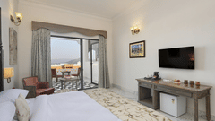 Fateh Vilas Udaipur - interior view of the Renaissance Room featuring a bed a television a balcony and white decor