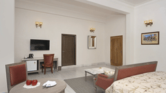 Fateh Vilas Udaipur - interior view of the suite featuring a television a mirror coffee table and a painting that is hanging on the wall